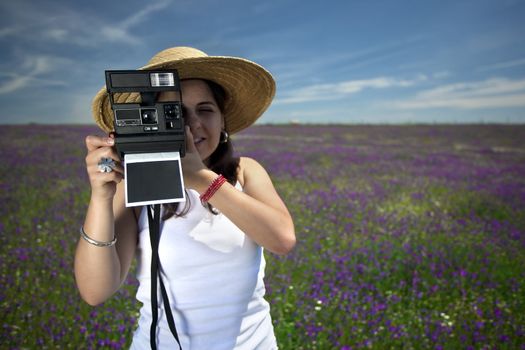 young woman with instant photo camera taking landscape pictures