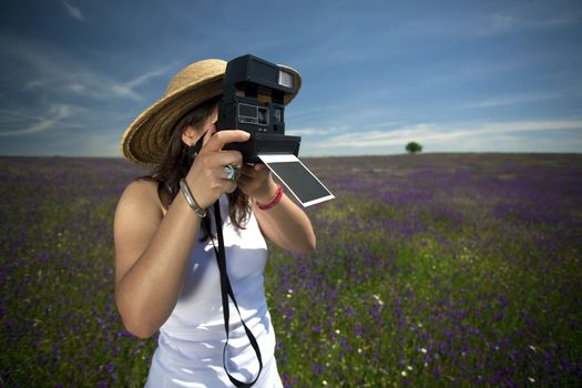 young woman with instant photo camera taking landscape pictures