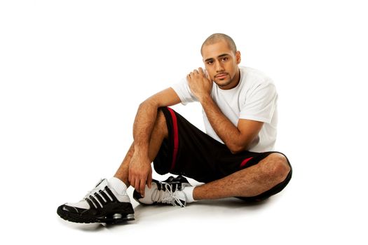 Sporty handsome African Hispanic guy sitting on floor, isolated