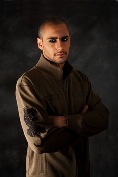 Handsome African Hispanic guy frowning with strong macho expression and dark eyes in green vest with black tiger on sleeve