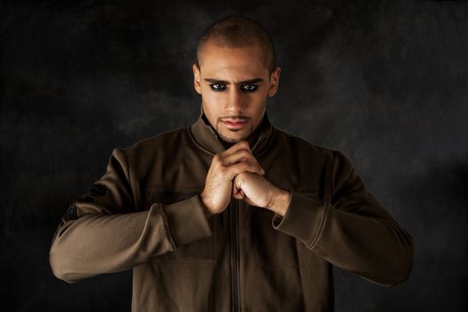 Handsome African Hispanic guy frowning with strong mad macho expression and dark eyes in green vest and hands in a fist