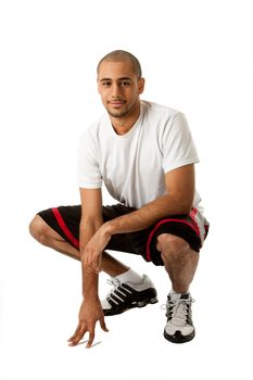 Sporty handsome African Hispanic guy crouching and hand on floor, isolated