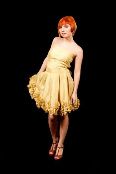 Beautiful Caucasian redhead woman in yellow cocktail dress standing tilted, isolated