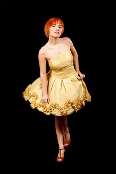Beautiful Caucasian redhead woman in yellow cocktail dress in playful pose, isolated