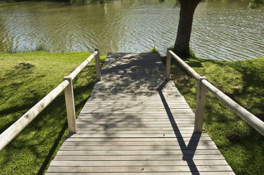 Wooden pathway leading to the river in a natural park
