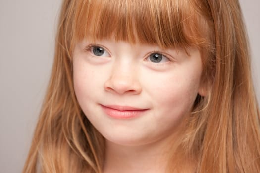 Portrait of an Adorable Red Haired Girl on a Grey Background.