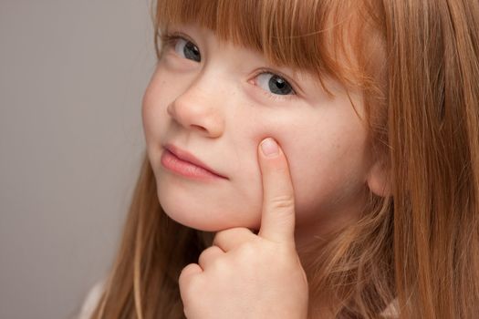 Portrait of an Adorable Red Haired Girl on a Grey Background.