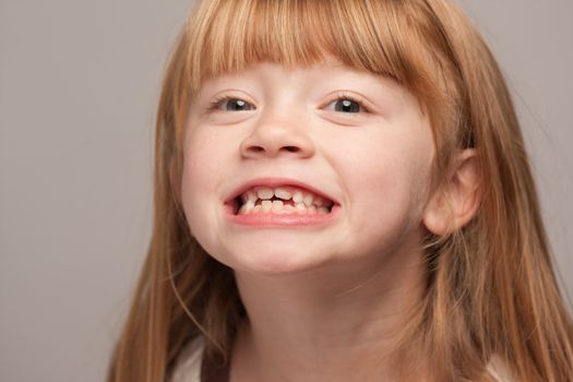 Portrait of an Adorable Red Haired Girl on a Grey Background.