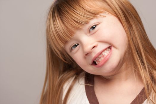 Portrait of an Adorable Red Haired Girl on a Grey Background.