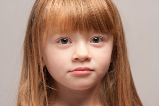 Portrait of an Adorable Red Haired Girl on a Grey Background.