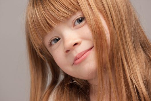 Portrait of an Adorable Red Haired Girl on a Grey Background.