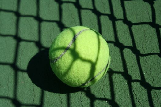 A Tennis ball near net with showdows