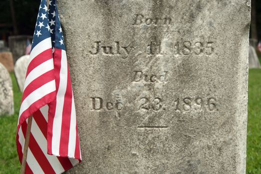 Old Gravestone with with US flag in a graveyard