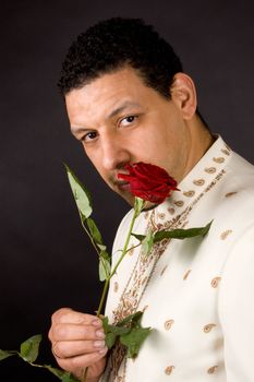 aruban male is smelling a beautiful red rose on black