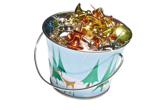 Miniature bucket with Holiday design, filled with brightly colored push pins.  Isolated on a white background.