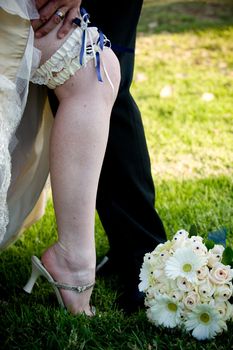 Groom’s hand on revealed bride's leg with blue and white garter exposed