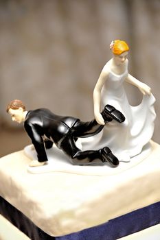 wedding figurine on cake with bride dragging the groom doll by the feet to the church symbolically