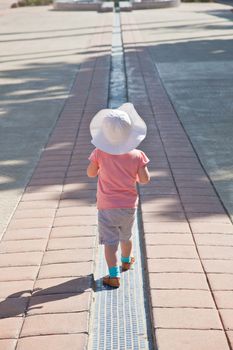 Cute little European toddler girl walking along the line.