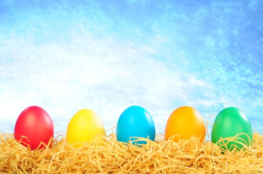five painted eggs on a straw on a clear sky background