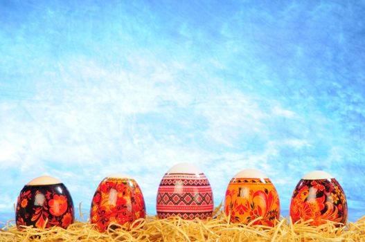 five brush painting eggs on yellow straw