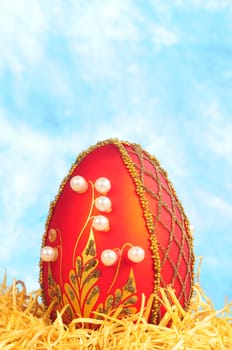 luxury easter egg in straw on blue background