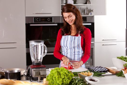 Beautiful brunette working in the kitchen cutting vegetables