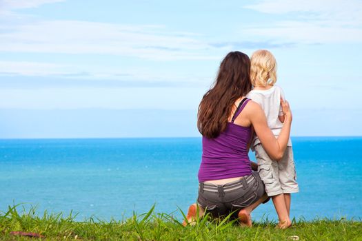 A sweet image of a a young mother and child looking at a beautiful ocean view together