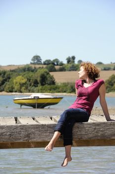 Girl sitting and sunbathing on landing stage in brittany