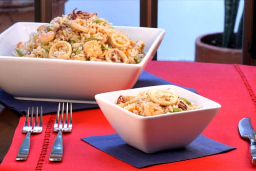 delicious calamari rice with assorted seafood and vegetables served on nice fancy table  