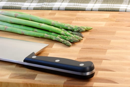 asparagus on fine wood cutting board with a six inches cleaver