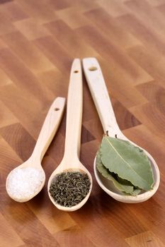 fancy wood spoons on fine wood cutting board with bay leaf ,coarse salt and ground pepper  great cooking ingredients 