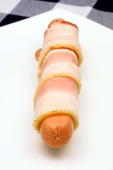 raw hot dog rapped in bacon o white plate 