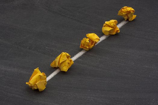 model of linear bus or backbone network with two endpoints made with yellow crumbled paper nodes, white chalk connection lines and blackboard with eraser smudges in background