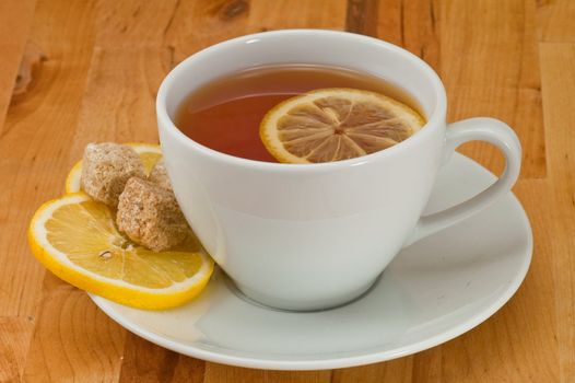 White porcelain cap of tea with sliced lemon and brown sugar on the wooden table