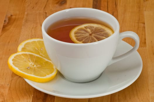 White porcelain cap of tea with sliced lemon on the wooden table