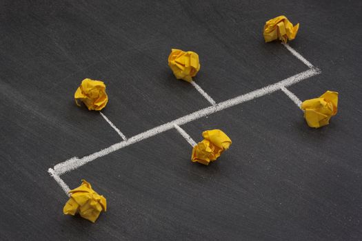 model of bus or backbone network with two endpoints made with yellow crumbled paper nodes, white chalk connection lines and blackboard with eraser smudges in background