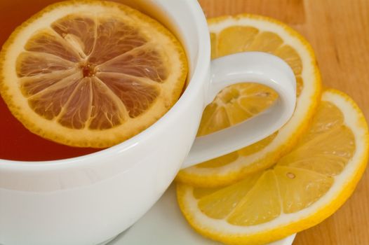 White porcelain cap of tea with sliced lemon on the wooden table