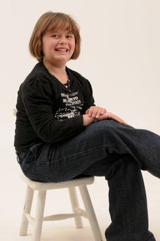 young beautiful  short brown hair teenager smiling with dimple in cheek sitting on a white chair