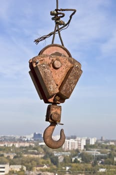 Building a rusty crane hook against the backdrop of the city.