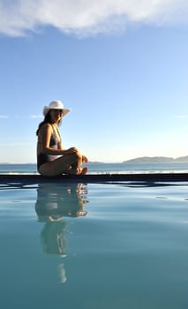 Woman relaxing on a swimming pool with a sea view
