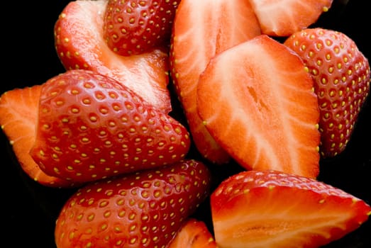 An arrangement of sliced strawberries on a black background