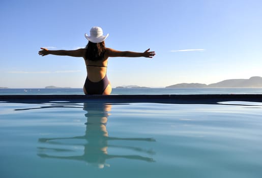 Woman relaxing on a swimming pool with a sea view
