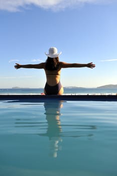 Woman relaxing on a swimming pool with a sea view
