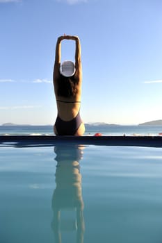 Woman relaxing on a swimming pool with a sea view
