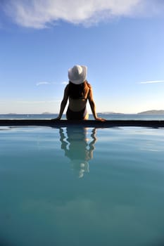 Woman relaxing on a swimming pool with a sea view
