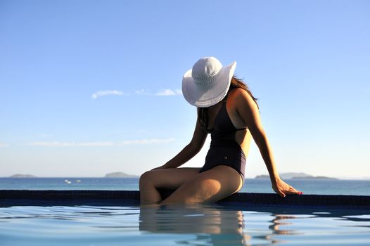 Woman relaxing on a swimming pool with a sea view
