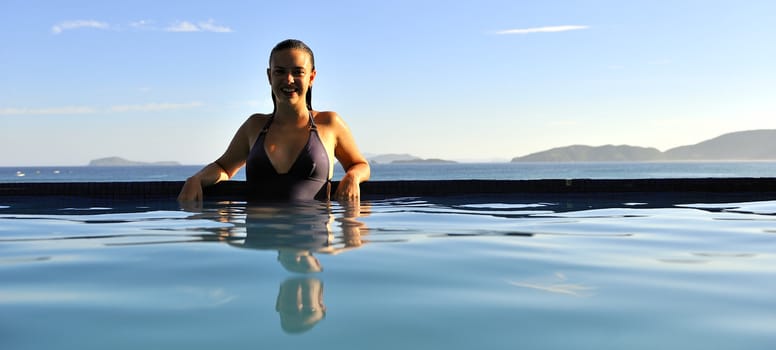 Woman relaxing on a swimming pool with a sea view
