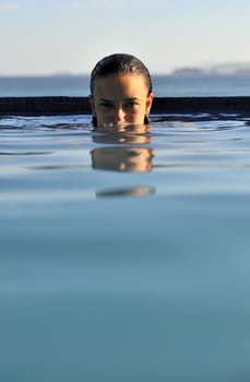 Woman relaxing on a swimming pool with a sea view
