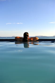 Woman relaxing on a swimming pool with a sea view
