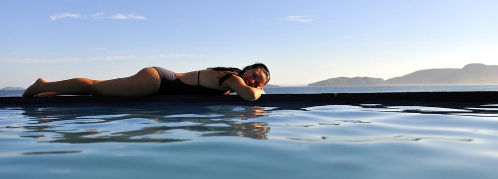 Woman relaxing on a swimming pool with a sea view
